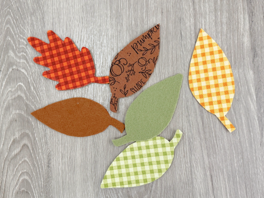 Image contains a variety of leaf shapes cut from different harvest fabric patterns.