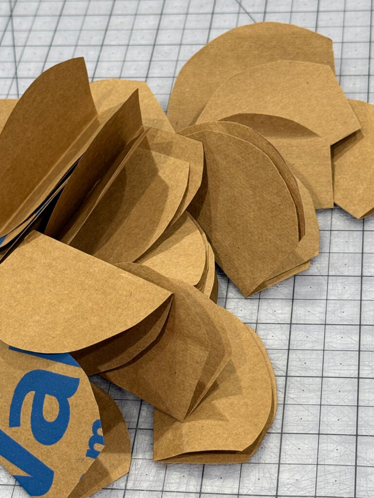 Image contains circles cut from a paper bag that have been folded in half and trimmed.