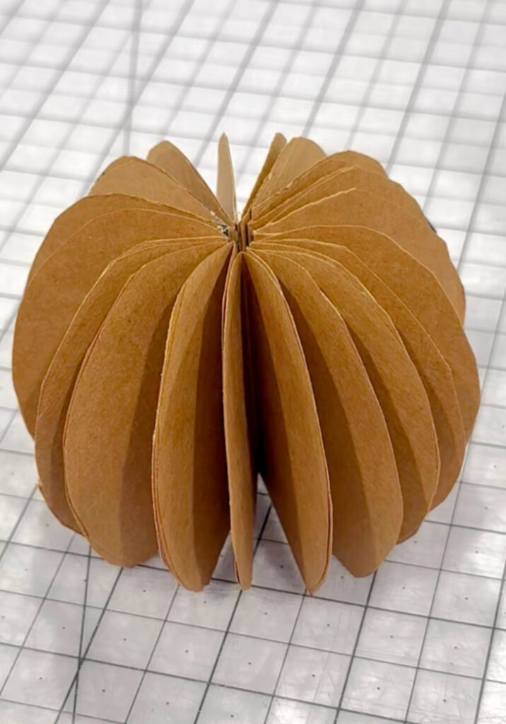 Image contains a partially completed paper bag pumpkin.
