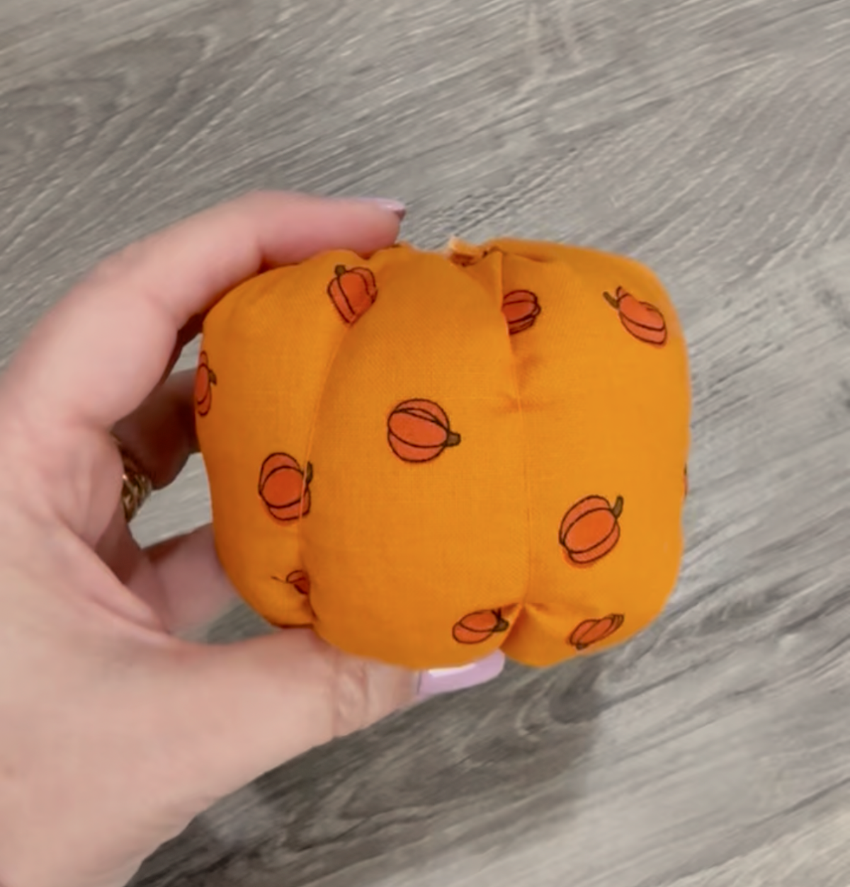 Image contains Amy's hand holding a partially completed fabric pumpkin.