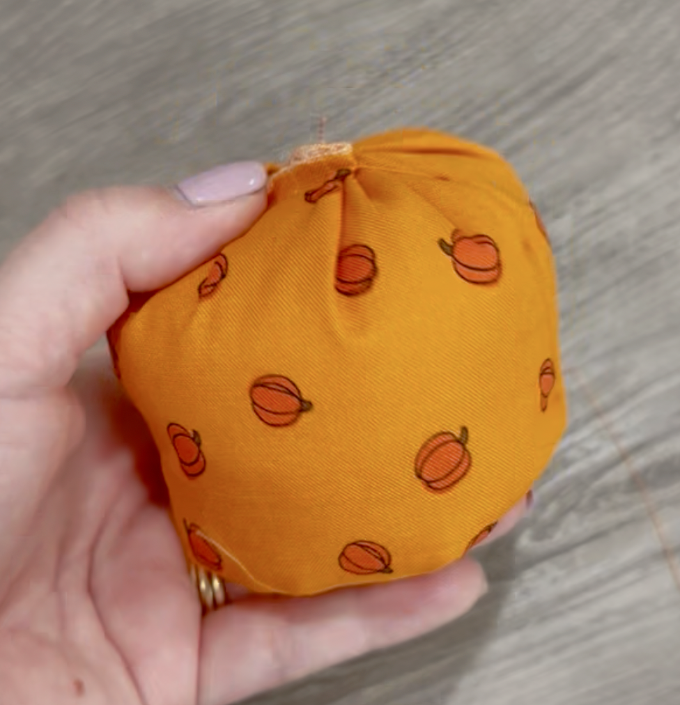 Image contains Amy's hand holding a partially completed fabric pumpkin.