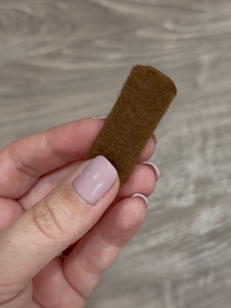 Image contains Amy's hand holding a rolled piece of brown felt.